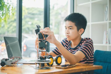 Asyalı çocuk teknoloji robotlarının çalışmalarını öğreniyor ve inceliyor. Teknoloji projesi için ev okulu ve bilim. Çocukluk çocukları hobisi eğlence yaşam tarzı oyuncakları robot teknolojisi.
