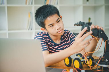 Asyalı çocuk teknoloji robotlarının çalışmalarını öğreniyor ve inceliyor. Teknoloji projesi için ev okulu ve bilim. Çocukluk çocukları hobisi eğlence yaşam tarzı oyuncakları robot teknolojisi.