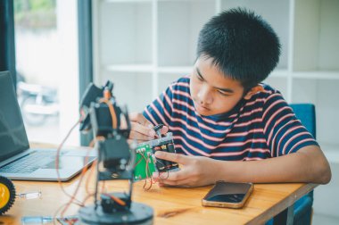 Asyalı çocuk teknoloji robotlarının çalışmalarını öğreniyor ve inceliyor. Teknoloji projesi için ev okulu ve bilim. Çocukluk çocukları hobisi eğlence yaşam tarzı oyuncakları robot teknolojisi.