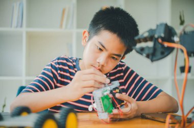 Asyalı çocuk teknoloji robotlarının çalışmalarını öğreniyor ve inceliyor. Teknoloji projesi için ev okulu ve bilim. Çocukluk çocukları hobisi eğlence yaşam tarzı oyuncakları robot teknolojisi.
