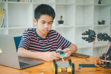 Asyalı çocuk teknoloji robotlarının çalışmalarını öğreniyor ve inceliyor. Teknoloji projesi için ev okulu ve bilim. Çocukluk çocukları hobisi eğlence yaşam tarzı oyuncakları robot teknolojisi.