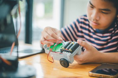 Asyalı çocuk teknoloji robotlarının çalışmalarını öğreniyor ve inceliyor. Teknoloji projesi için ev okulu ve bilim. Çocukluk çocukları hobisi eğlence yaşam tarzı oyuncakları robot teknolojisi.