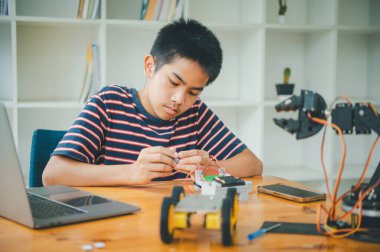 Asyalı çocuk teknoloji robotlarının çalışmalarını öğreniyor ve inceliyor. Teknoloji projesi için ev okulu ve bilim. Çocukluk çocukları hobisi eğlence yaşam tarzı oyuncakları robot teknolojisi.