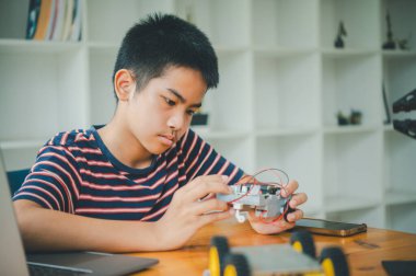 Asyalı çocuk teknoloji robotlarının çalışmalarını öğreniyor ve inceliyor. Teknoloji projesi için ev okulu ve bilim. Çocukluk çocukları hobisi eğlence yaşam tarzı oyuncakları robot teknolojisi.