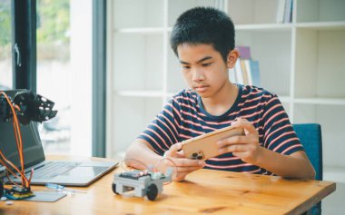Asyalı çocuk teknoloji robotlarının çalışmalarını öğreniyor ve inceliyor. Teknoloji projesi için ev okulu ve bilim. Çocukluk çocukları hobisi eğlence yaşam tarzı oyuncakları robot teknolojisi.