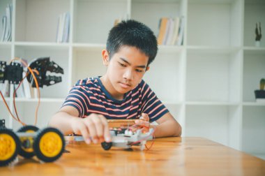 Asyalı çocuk teknoloji robotlarının çalışmalarını öğreniyor ve inceliyor. Teknoloji projesi için ev okulu ve bilim. Çocukluk çocukları hobisi eğlence yaşam tarzı oyuncakları robot teknolojisi.