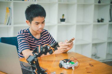 Asyalı çocuk teknoloji robotlarının çalışmalarını öğreniyor ve inceliyor. Teknoloji projesi için ev okulu ve bilim. Çocukluk çocukları hobisi eğlence yaşam tarzı oyuncakları robot teknolojisi.