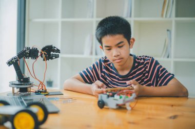 Asyalı çocuk teknoloji robotlarının çalışmalarını öğreniyor ve inceliyor. Teknoloji projesi için ev okulu ve bilim. Çocukluk çocukları hobisi eğlence yaşam tarzı oyuncakları robot teknolojisi.