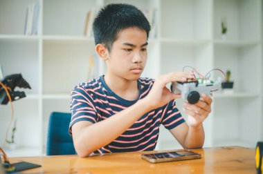 Asyalı çocuk teknoloji robotlarının çalışmalarını öğreniyor ve inceliyor. Teknoloji projesi için ev okulu ve bilim. Çocukluk çocukları hobisi eğlence yaşam tarzı oyuncakları robot teknolojisi.