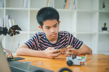 Asyalı çocuk teknoloji robotlarının çalışmalarını öğreniyor ve inceliyor. Teknoloji projesi için ev okulu ve bilim. Çocukluk çocukları hobisi eğlence yaşam tarzı oyuncakları robot teknolojisi.