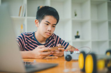 Asyalı çocuk teknoloji robotlarının çalışmalarını öğreniyor ve inceliyor. Teknoloji projesi için ev okulu ve bilim. Çocukluk çocukları hobisi eğlence yaşam tarzı oyuncakları robot teknolojisi.