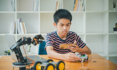 Asyalı çocuk teknoloji robotlarının çalışmalarını öğreniyor ve inceliyor. Teknoloji projesi için ev okulu ve bilim. Çocukluk çocukları hobisi eğlence yaşam tarzı oyuncakları robot teknolojisi.