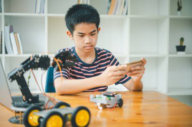 Asyalı çocuk teknoloji robotlarının çalışmalarını öğreniyor ve inceliyor. Teknoloji projesi için ev okulu ve bilim. Çocukluk çocukları hobisi eğlence yaşam tarzı oyuncakları robot teknolojisi.
