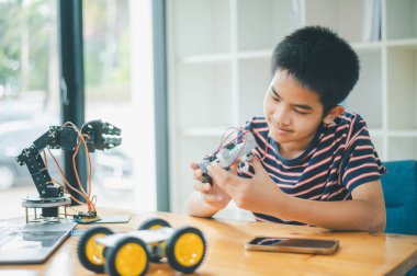 Asyalı çocuk teknoloji robotlarının çalışmalarını öğreniyor ve inceliyor. Teknoloji projesi için ev okulu ve bilim. Çocukluk çocukları hobisi eğlence yaşam tarzı oyuncakları robot teknolojisi.