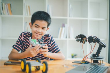 Asyalı çocuk teknoloji robotlarının çalışmalarını öğreniyor ve inceliyor. Teknoloji projesi için ev okulu ve bilim. Çocukluk çocukları hobisi eğlence yaşam tarzı oyuncakları robot teknolojisi.