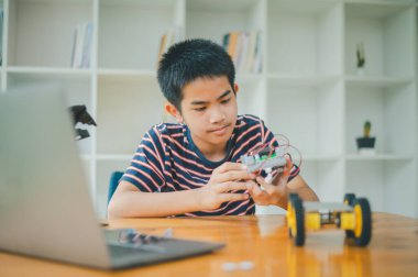 Asyalı çocuk teknoloji robotlarının çalışmalarını öğreniyor ve inceliyor. Teknoloji projesi için ev okulu ve bilim. Çocukluk çocukları hobisi eğlence yaşam tarzı oyuncakları robot teknolojisi.