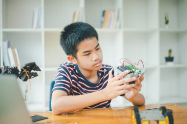 Asyalı çocuk teknoloji robotlarının çalışmalarını öğreniyor ve inceliyor. Teknoloji projesi için ev okulu ve bilim. Çocukluk çocukları hobisi eğlence yaşam tarzı oyuncakları robot teknolojisi.