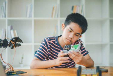 Asyalı çocuk teknoloji robotlarının çalışmalarını öğreniyor ve inceliyor. Teknoloji projesi için ev okulu ve bilim. Çocukluk çocukları hobisi eğlence yaşam tarzı oyuncakları robot teknolojisi.