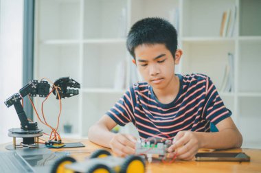 Asyalı çocuk teknoloji robotlarının çalışmalarını öğreniyor ve inceliyor. Teknoloji projesi için ev okulu ve bilim. Çocukluk çocukları hobisi eğlence yaşam tarzı oyuncakları robot teknolojisi.
