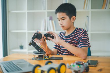 Asyalı çocuk teknoloji robotlarının çalışmalarını öğreniyor ve inceliyor. Teknoloji projesi için ev okulu ve bilim. Çocukluk çocukları hobisi eğlence yaşam tarzı oyuncakları robot teknolojisi.