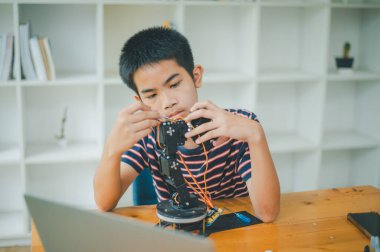 Asyalı çocuk teknoloji robotlarının çalışmalarını öğreniyor ve inceliyor. Teknoloji projesi için ev okulu ve bilim. Çocukluk çocukları hobisi eğlence yaşam tarzı oyuncakları robot teknolojisi.