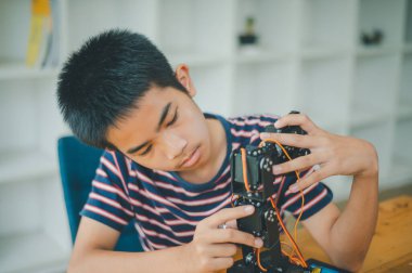 Asyalı çocuk teknoloji robotlarının çalışmalarını öğreniyor ve inceliyor. Teknoloji projesi için ev okulu ve bilim. Çocukluk çocukları hobisi eğlence yaşam tarzı oyuncakları robot teknolojisi.