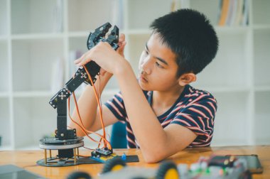 Asyalı çocuk teknoloji robotlarının çalışmalarını öğreniyor ve inceliyor. Teknoloji projesi için ev okulu ve bilim. Çocukluk çocukları hobisi eğlence yaşam tarzı oyuncakları robot teknolojisi.