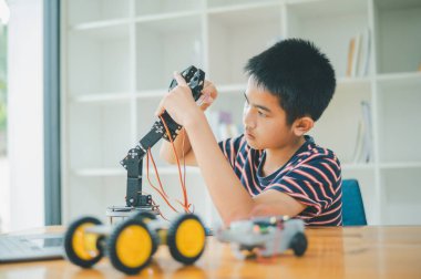 Asyalı çocuk teknoloji robotlarının çalışmalarını öğreniyor ve inceliyor. Teknoloji projesi için ev okulu ve bilim. Çocukluk çocukları hobisi eğlence yaşam tarzı oyuncakları robot teknolojisi.