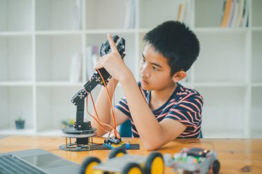 Asyalı çocuk teknoloji robotlarının çalışmalarını öğreniyor ve inceliyor. Teknoloji projesi için ev okulu ve bilim. Çocukluk çocukları hobisi eğlence yaşam tarzı oyuncakları robot teknolojisi.