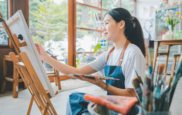 Art student drawing with watercolor painting on canvas doing some art projects on studio workshop