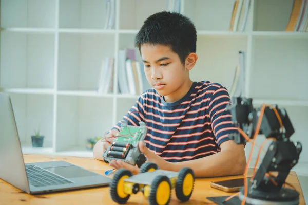 Asyalı çocuk teknoloji robotlarının çalışmalarını öğreniyor ve inceliyor. Teknoloji projesi için ev okulu ve bilim. Çocukluk çocukları hobisi eğlence yaşam tarzı oyuncakları robot teknolojisi.