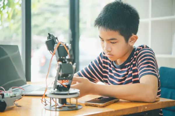 Asyalı çocuk teknoloji robotlarının çalışmalarını öğreniyor ve inceliyor. Teknoloji projesi için ev okulu ve bilim. Çocukluk çocukları hobisi eğlence yaşam tarzı oyuncakları robot teknolojisi.