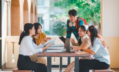 Bir grup genç üniversite öğrencisi ödev yaparken danışmanlık yapıyor, araştırma planında işbirliği yapıyor kavramları ve stratejileri tartışıyorlar. Dizüstü bilgisayarlarda ve tablet bilgisayarlarda sunumları hazırlayın.