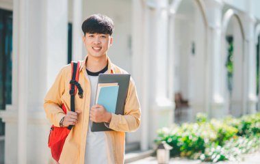 Öğrenmek için okula giderken elinde kitapla mutlu gülümseyen bir öğrenci..