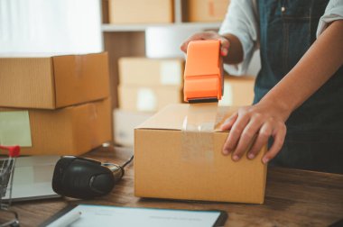 Çevrimiçi küçük işletme sahibi çevrimiçi alışveriş konseptine göre müşteriler için ürünler paketliyor.