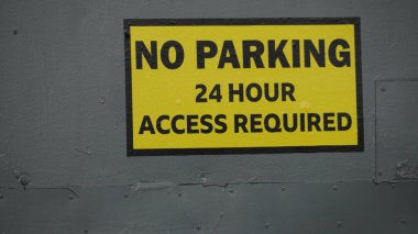 Endüstriyel birimlere erişim gerekliliklerinden dolayı sanayi bölgelerinde park işareti yok. Sarı arkaplanda siyah harfler,