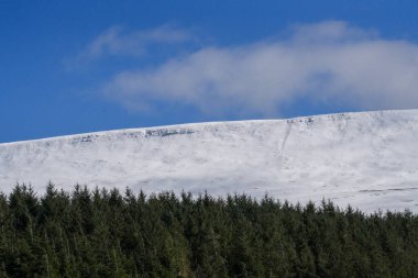 Galler dağ kışı manzarası. Storey Arms 'ın üstündeki dağların tepesinde Brecon Beacons' da kar yağıyor. Buzlu koşullar ama güneş parlıyor ve tepelerdeki karları eritti..