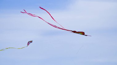 Kelebek şekilli uçurtma, Knap 'te bir aile uçurtma festivalinde uçuruluyor Barry. Uzun kuyruğu rüzgarı yakalar ve yükselir. Şekil, ince bulutlarla dağılmış mavi gökyüzüne karşı duruyor..