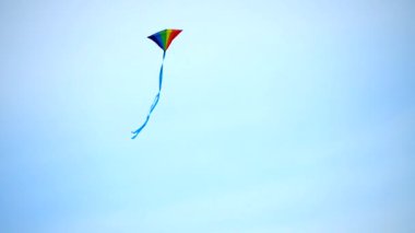 Gökkuşağı renginde elmas bir uçurtma havada uçuyor. Esinti onu yakalayınca, zıplıyor, eğiliyor ve dönüyor. Uzun kuyruklar arkalarında iz bırakır ve gökyüzünde desenler oluştururlar. Çekimde kullanılabilir alanı kopyala