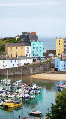 Tenby, Pembrokeshire, Galler - 2 Temmuz 2024: Güzel renkli liman binalarıyla Tenby limanına bakıyorum. Prens Albert 'in anısına dikilen heykel, kalenin arkasındaki tepede duruyor.. 