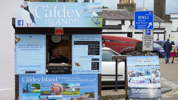 stock image Tenby, Pembrokeshire, Wales - July 02 2024: At the entrance of the Tenby harbour there is a small pale blue hut selling boat trips to Caldy Island. There are pictures to attract bookings