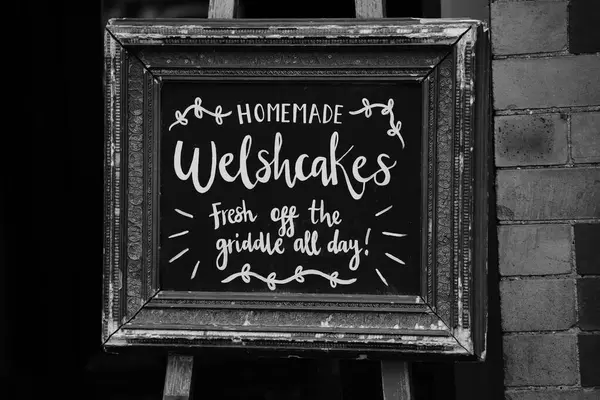 stock image Tenby, Pembrokeshire, Wales July 02 2024:  Black and white photograph of a sign in Tenby's high street advertising welsh-cakes, fresh off the griddle, in one of Wales most popular tourist resorts.