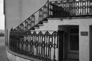 Tenby, Pembrokeshire, Wales, July 02 2024; Black and white photograph of an imposing building on the cliffs of Tenby's beach front called Gunfort mansion with wrought iron work around the building clipart