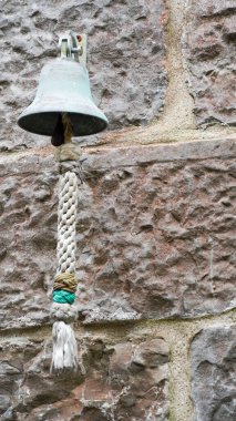 Old metal bell on a stone wall outside the Brewery in Sergeants Lane, Tenby which was a famous and historic trading route clipart