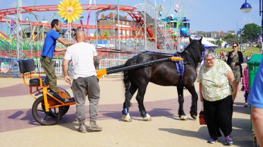 Barry Island, Vale of Glam, Wales, Aug 27 2024: A sunny summer bank holiday, guaranteed to draw the crowds for beach time, ice-cream, fish and chips, souvenir shopping and fun in amusement arcades.    clipart