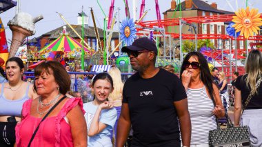 Barry Island, Vale of Glamorgan, Wales - Aug 27 2024: The bank holiday attracts families from multi ethnic backgrounds and cultures all enjoying the fun of the promenade with its children's fun rides. clipart