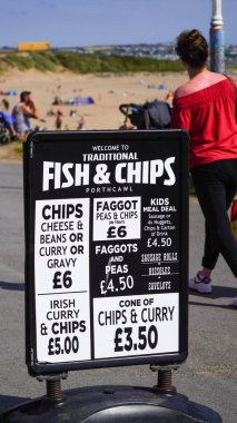 Porthcawl, Bridgend, Wales 17 Ağustos 2024: Tüm geleneksel plajların reklamını yapan siyah-beyaz bir tabela İngilizler tarafından balık ve patates cipsi, İrlanda köri sosu, sigara ve bezelye ile sevilen yiyecekleri aldı 