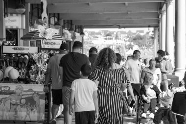 Barry Island, Barry, Vale of Glam, Wales - Aug 27 2024: People visit the western shelter at Barry Island, made famous by TV show Gavin and Stacey, with its amusement arcades and fish and chip shops. clipart