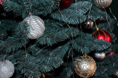 Noel arkaplanı. Yeşil arka planda Noel ağacı, çelenkler, kırmızı toplar ve gümüş Noel süslemeleri