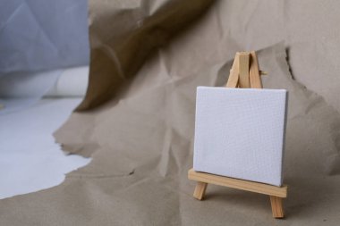 easel with empty canvas on craft paper